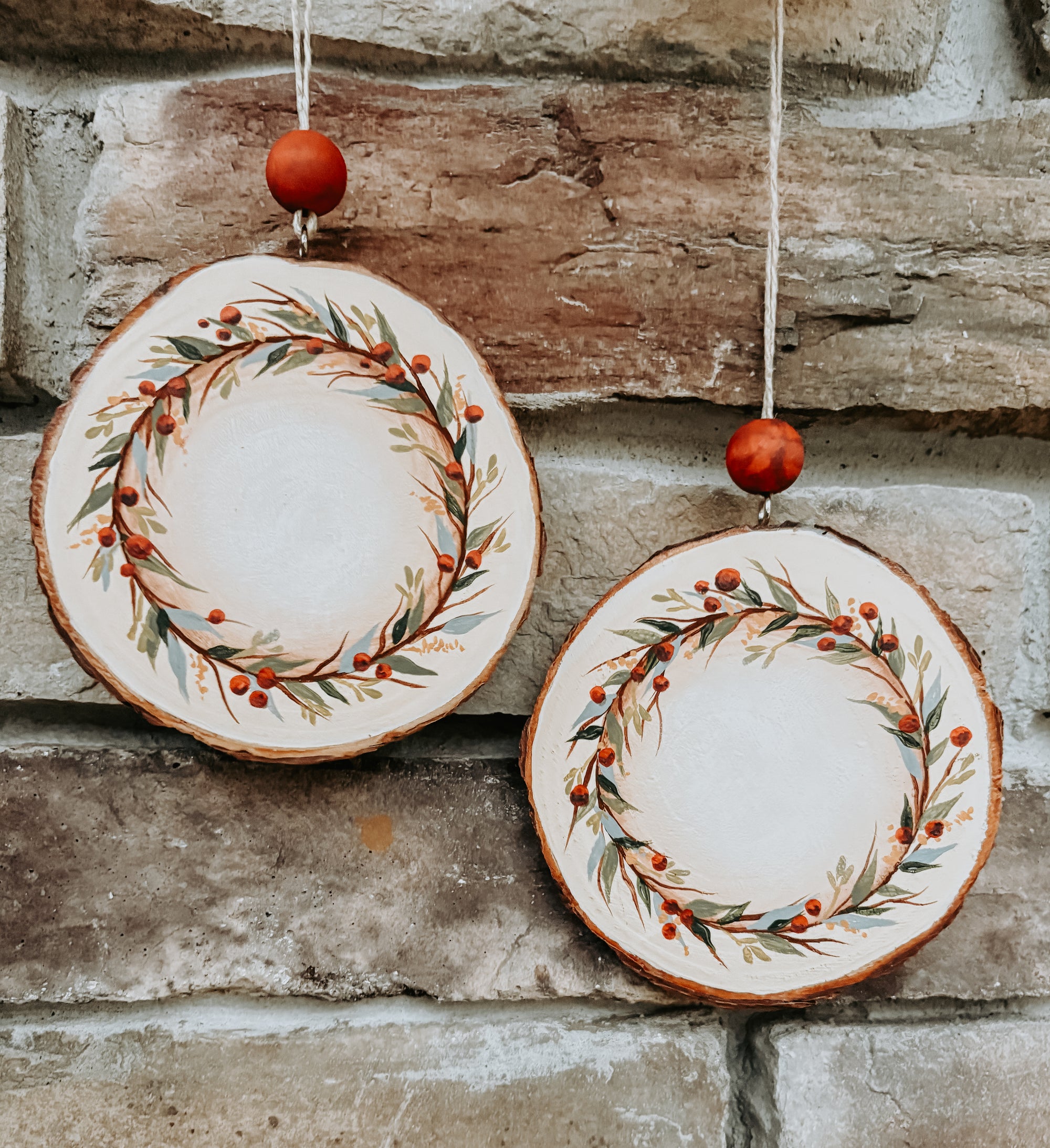 Hand painted holiday ornaments hanging in front of a brick background